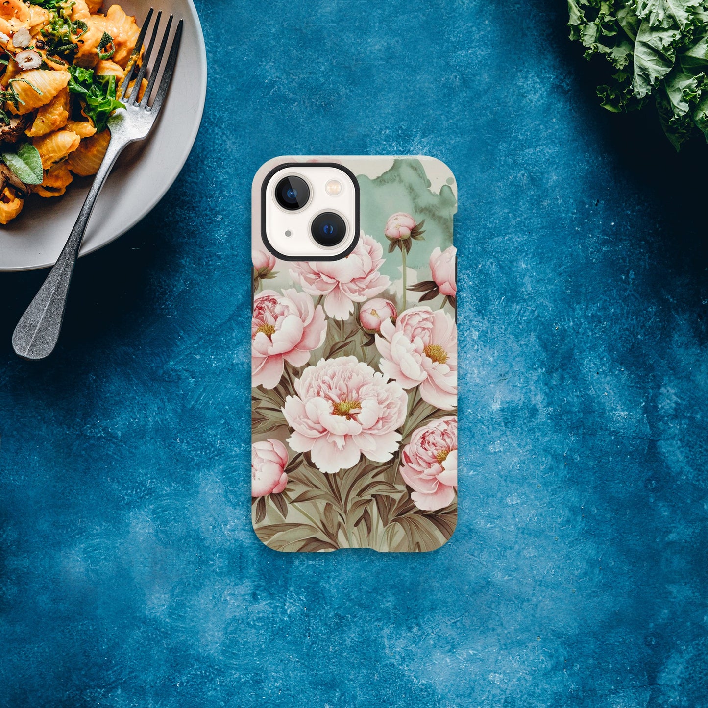 Protect your iPhone in style with a dual-layer tough case featuring pink peonies on a mint green background. Fits iPhone 12+ and supports wireless charging.